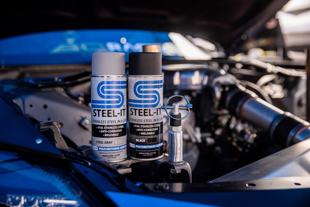 Dwa spraye farby STEEL-IT umieszczone na silniku pod otwartą klapą samochodu przeznaczonego do driftingu, prezentujące idealne rozwiązanie do ochrony i personalizacji pojazdów w ekstremalnych warunkach sportu motorowego